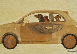 Intarsio ligneo di Capitan Morgan raffigurante una Fiat 500 con una famiglia di bassotti a bordo, realizzato con legni naturali e dettagli in colori acrilici, in stile ironico e affettuoso.