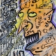 Volto arancione e giallo colmo di simboli e micro-figure su sfondo viola e nero, opera surreale e notturna di Emiliano Dalle Piagge Uodi.