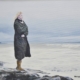 Donna solitaria che contempla il mare d’inverno, pittura realistica luminosa di Giovanni Graziani, atmosfera fredda e luce invernale sul mare.