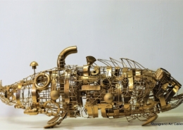 Scultura “Gold Fish” di Marco Cavalieri, pesce dorato realizzato con materiali di riciclo, metallo e componenti meccaniche.