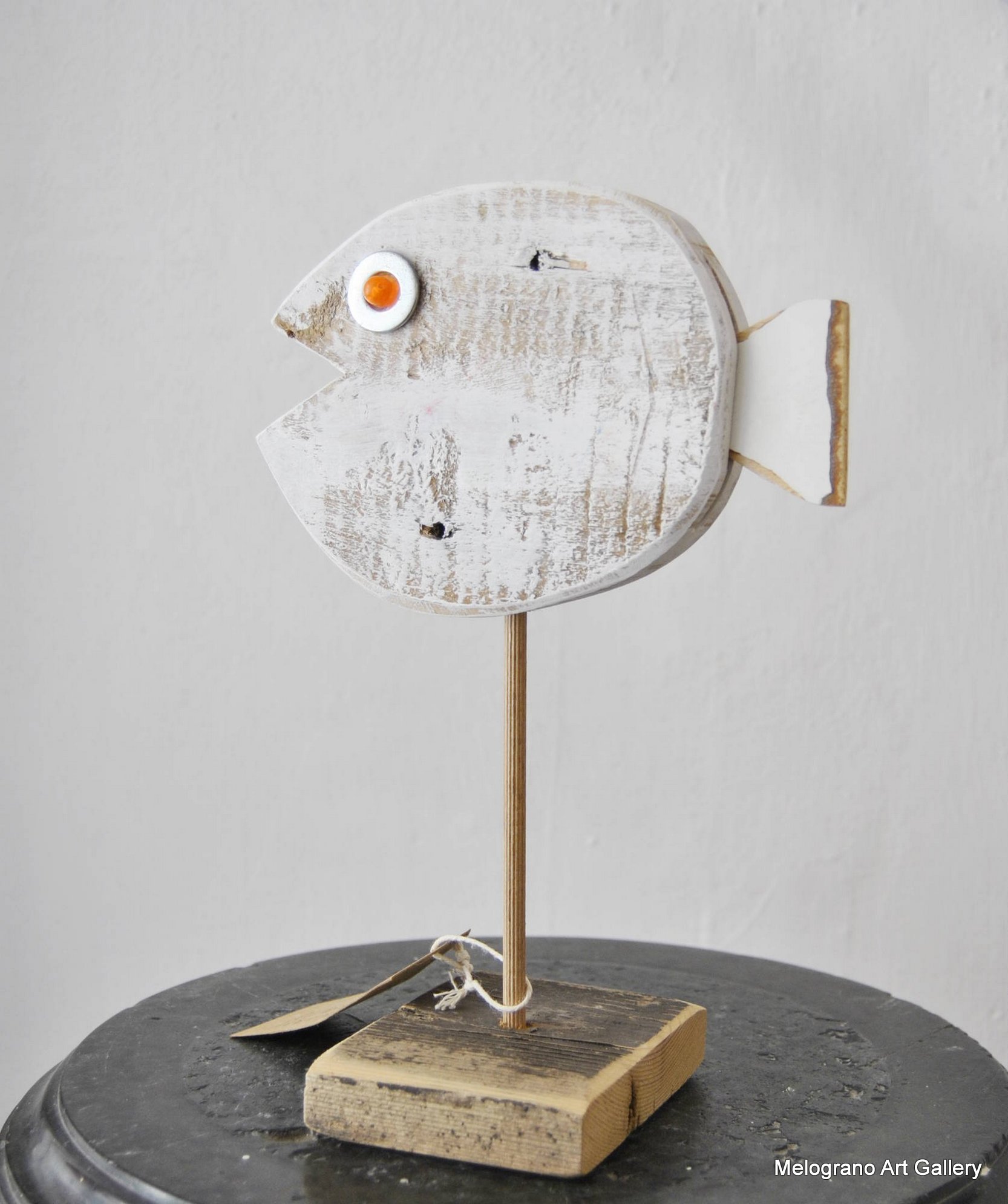 scultura sagomata pesciolino bianco su piedistallo in legno con asta metallica