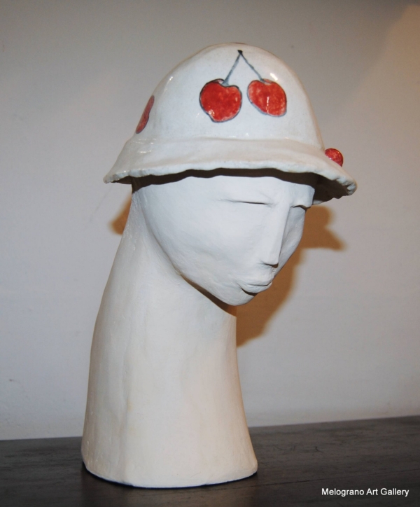 scultura in terracotta bianca con cappello lucido ornato di ciliegie rosse di Floriana Gerosa